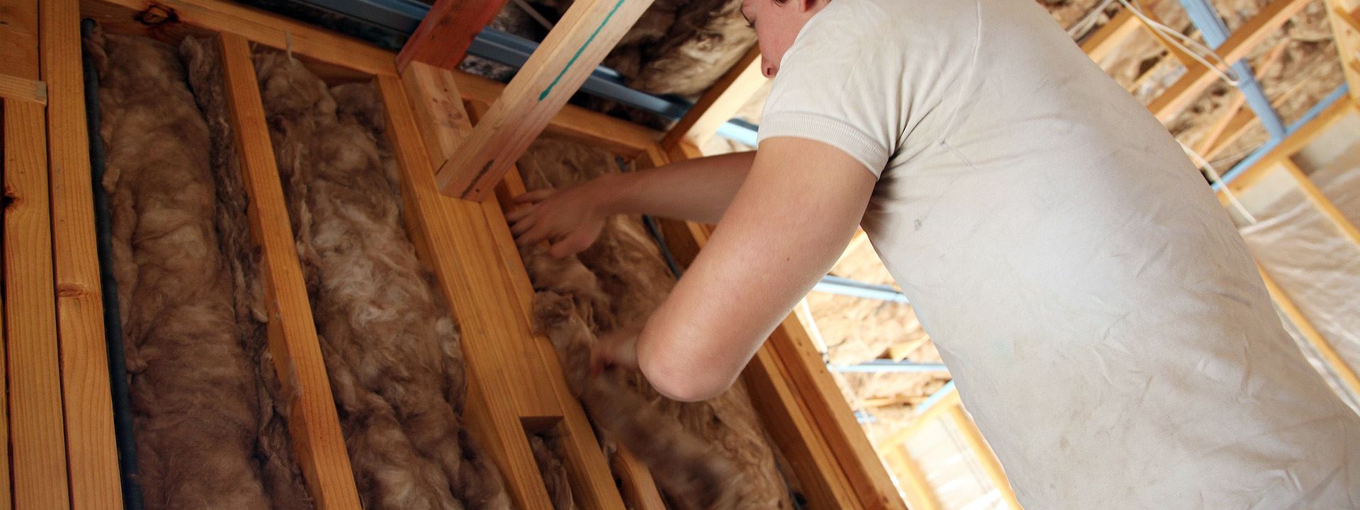 Person installing insulation in a wall